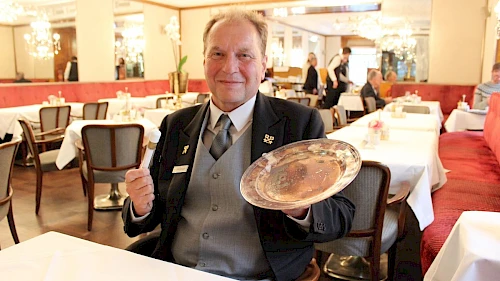 Chefconcierge Manfred Grassauer mit Silberteller und Schlüssel aus dem Hotel Imperial Hotel Imperial Chefconcierge im Interview
