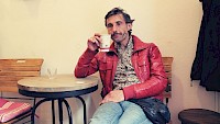 Tom Vogel in roter Jacke beim Kaffee trinken