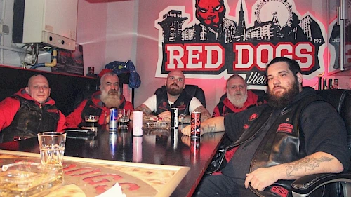 Red-Dogs-Biker im Doghouse Vienna Red-Dogs-Biker im Doghouse Vienna mit Red-Dogs-Logo im Hintergrund