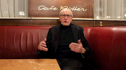 Im Talk: Konrad Paul Liessmann im Café Ritter gestikulierend im dunklen Anzug